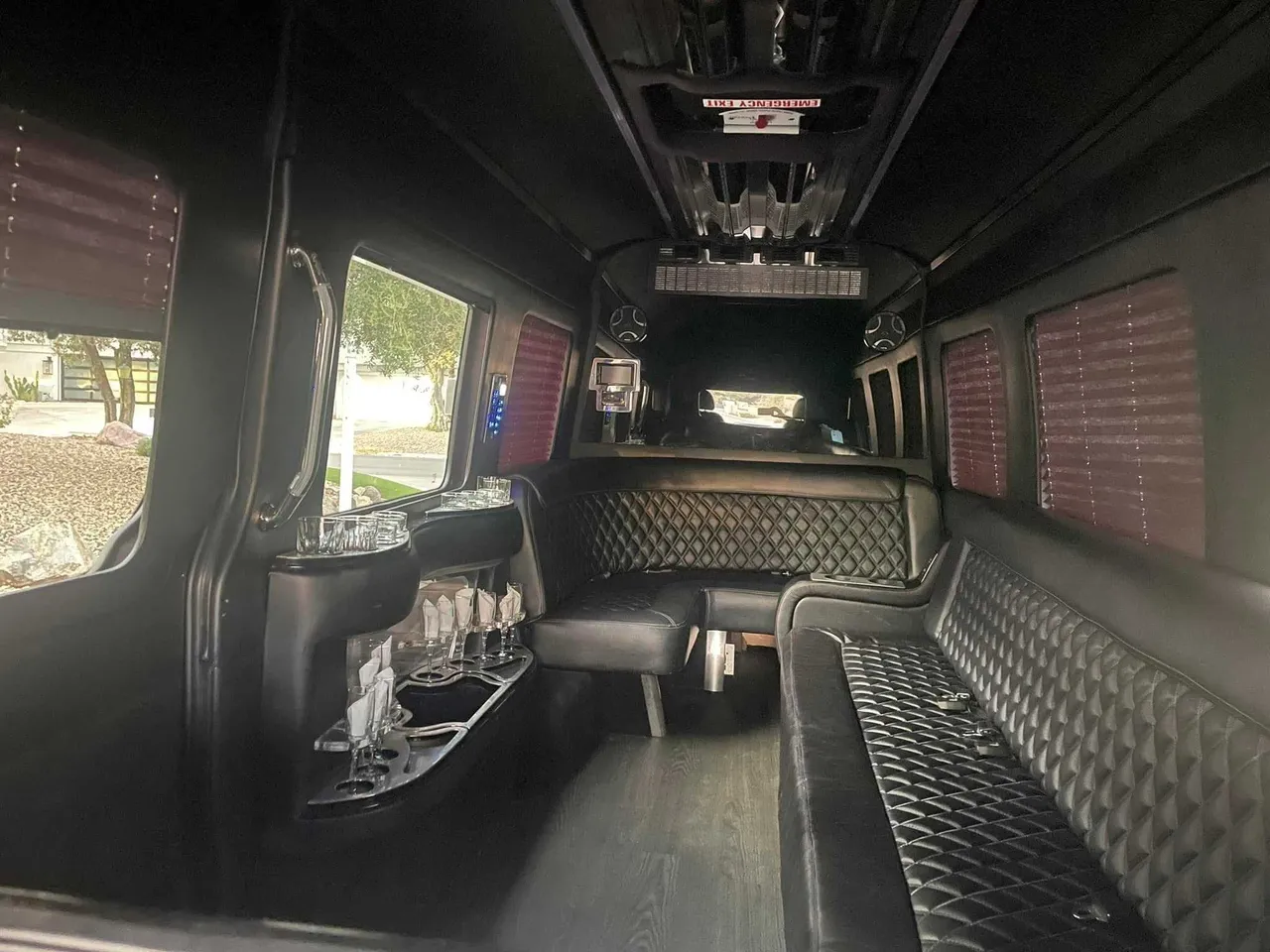 Mercedes Limo Sprinter interior with perimeter lounge seating, window shades and bar area for party bus rental in Pinetta, FL