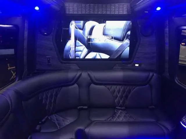 Mercedes-Benz Party Bus interior with sofa-style seating, LED accent lighting and TV screens for prom car rental in Burson, CA
