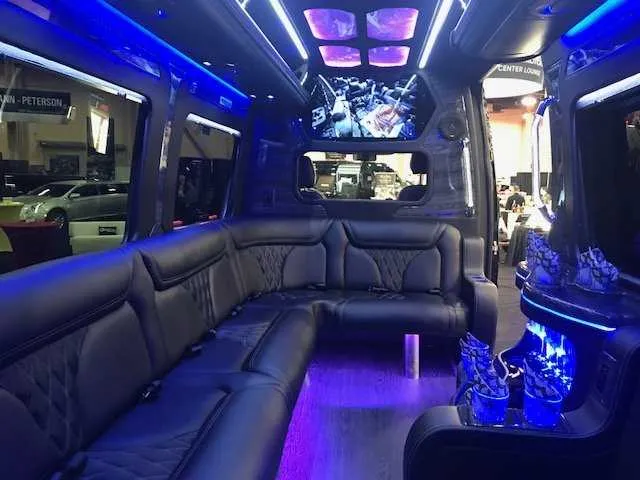Mercedes-Benz Party Bus interior with sofa-style seating, LED accent lighting and LED ceiling lighting for prom car rental in Burson, CA
