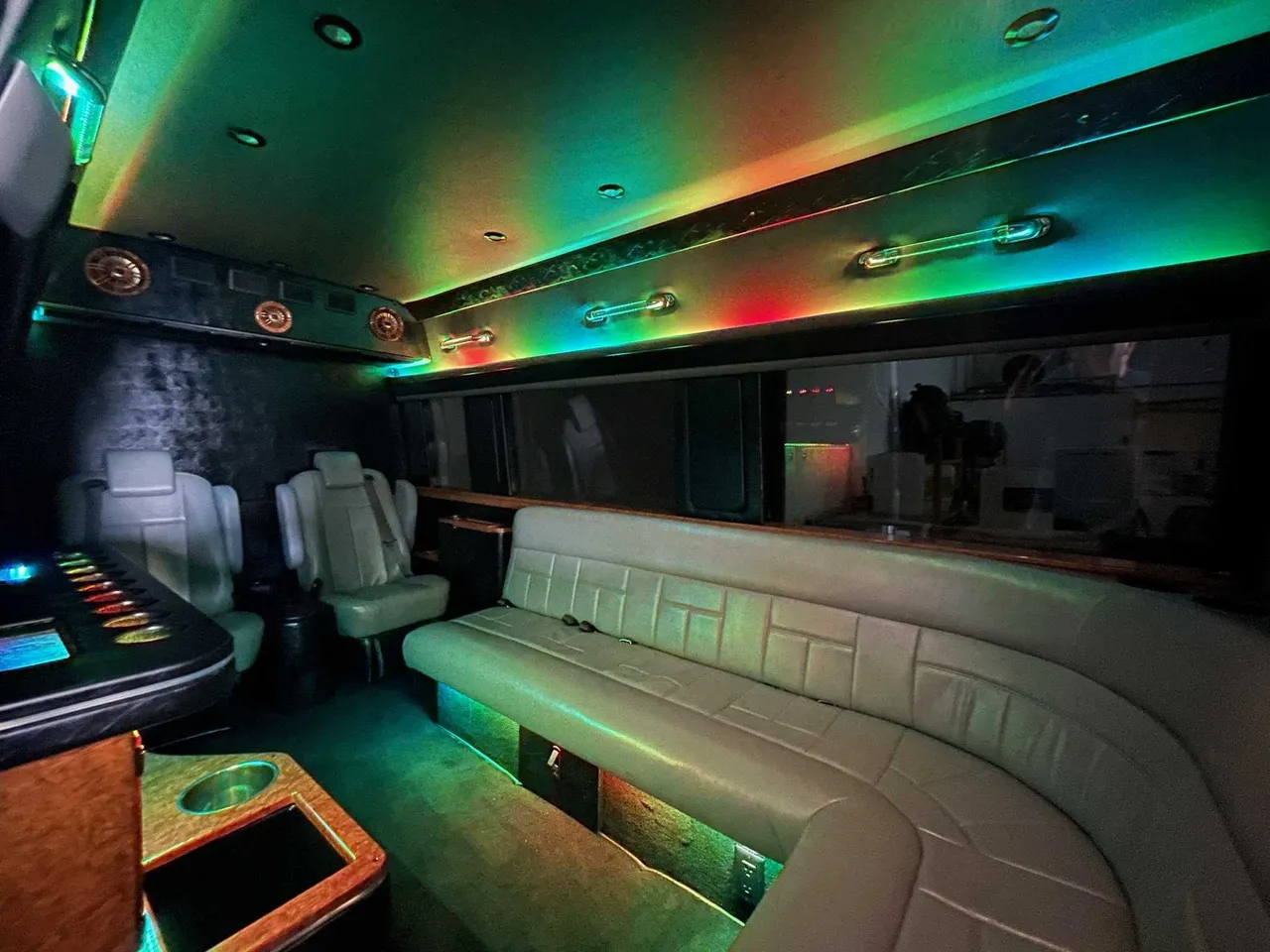 Mercedes Sprinter Limo interior with sofa-style seating, captain's chairs and LED accent lighting for party bus rental in Pinetta, FL