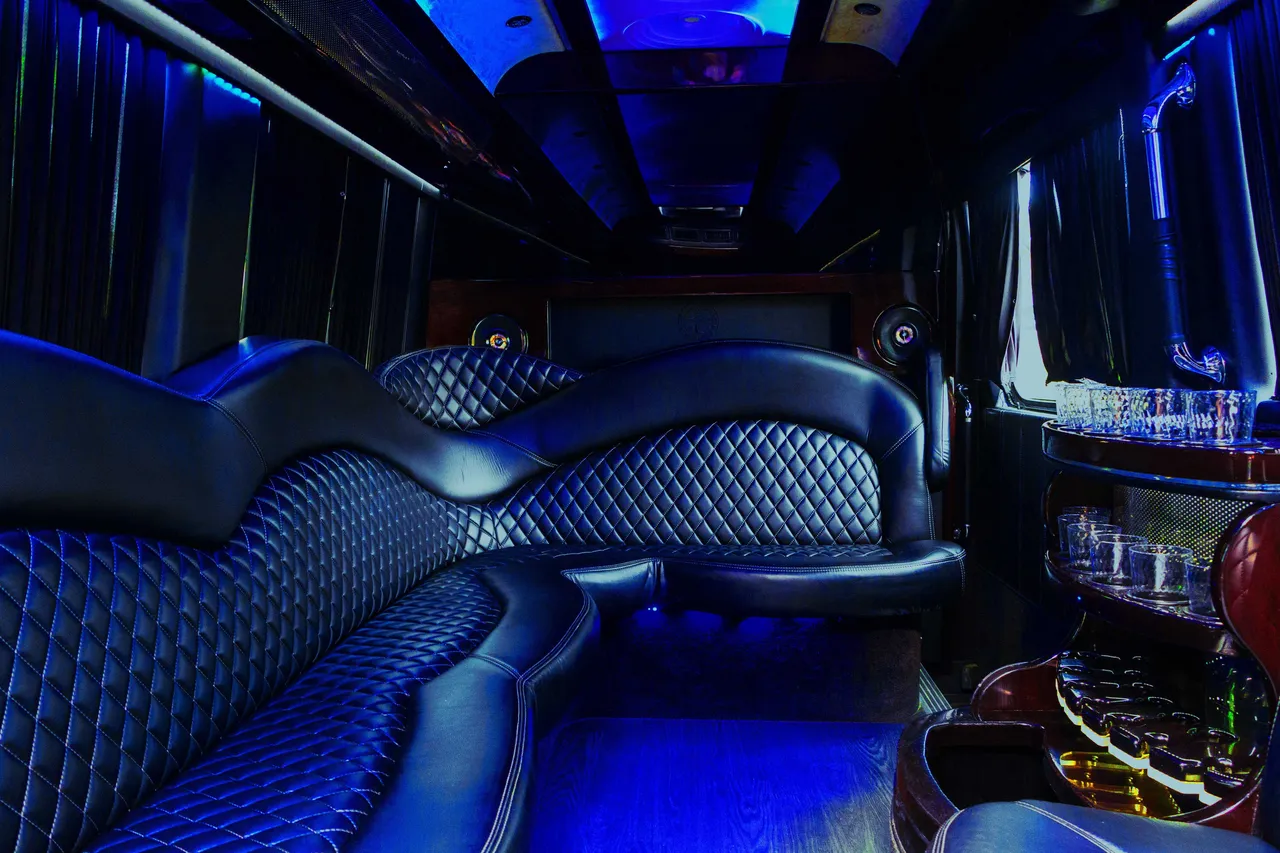 Mercedes Sprinter Limo interior with sofa-style seating, window shades and bar area for party bus rental