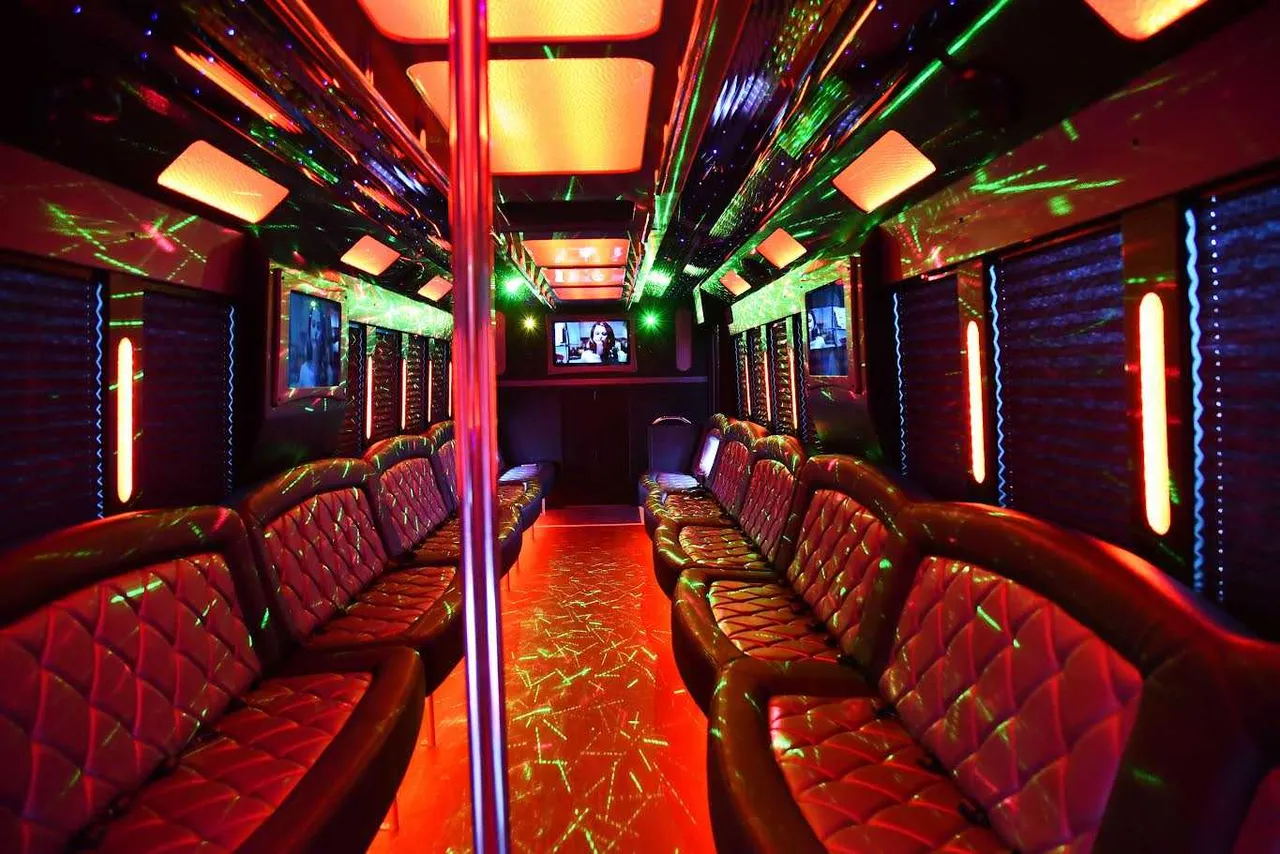 50 Passenger Party Bus interior with perimeter lounge seating, window shades and LED accent lighting for party bus rental in West Orange, NJ