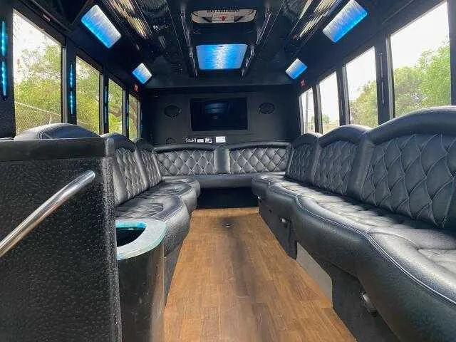 24 Passenger Party Bus interior with perimeter lounge seating, LED accent lighting and LED ceiling lighting for party bus rental in Burbank, CA
