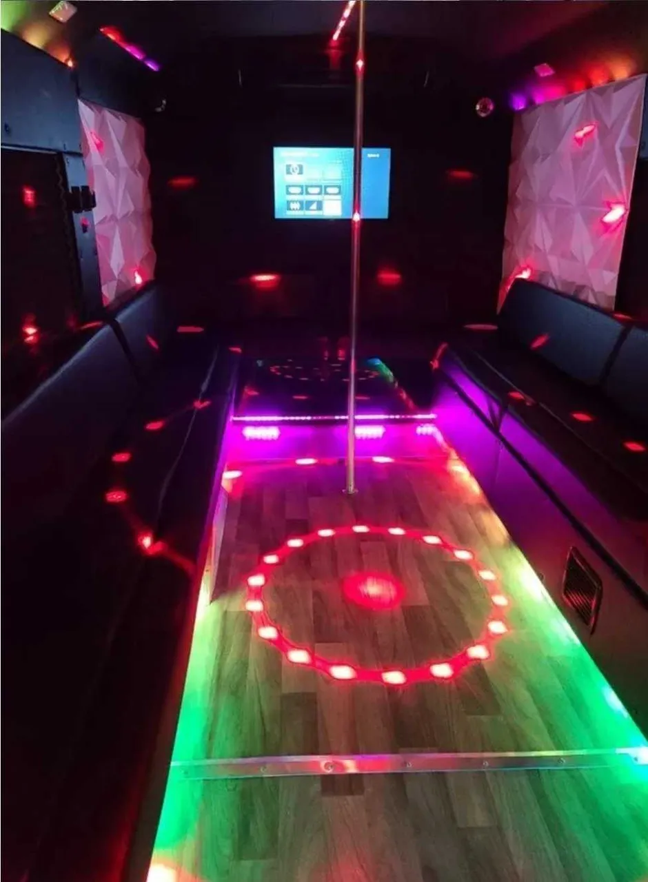 Tuxedo Party Bus interior with perimeter lounge seating, LED accent lighting and lit dance floor for party bus rental in Schertz, TX